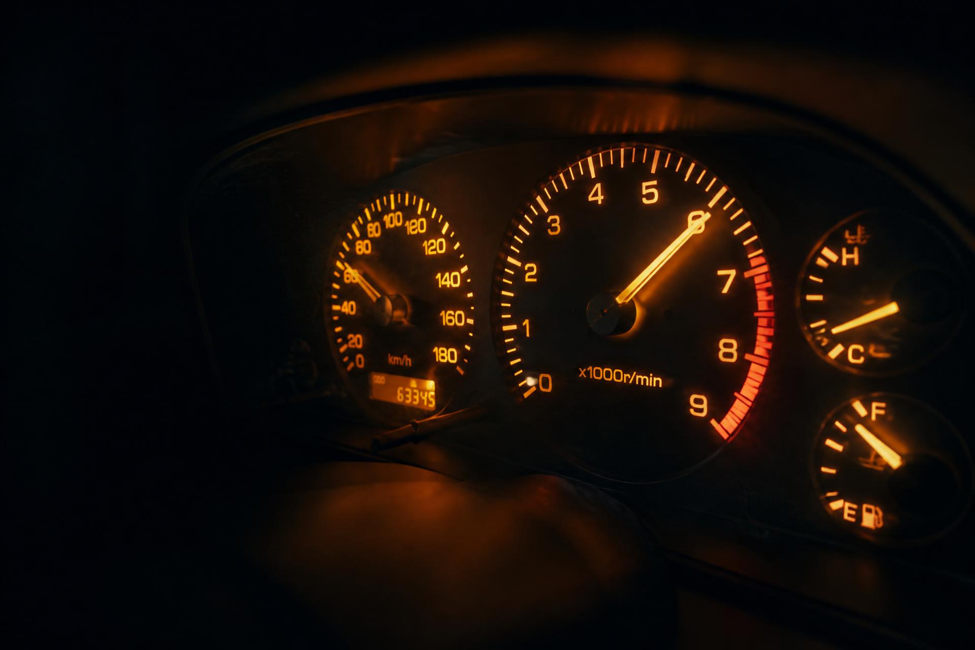 Restored Nissan JDM instrument cluster lit at night with amber backlight, tachometer needle mid-sweep